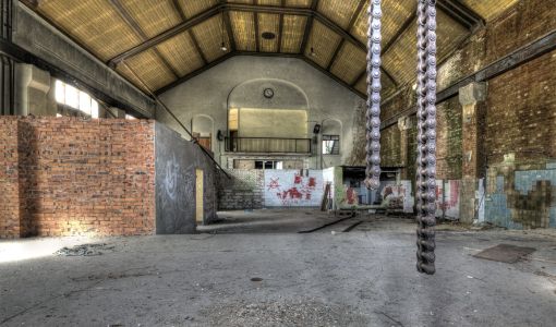 Geräumige Industriehalle mit Ketten und Graffiti.